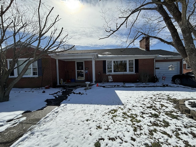 single story home featuring an attached garage, a chimney, and brick siding