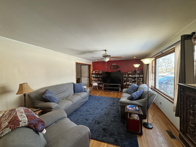 living room with crown molding, wood finished floors, visible vents, and a ceiling fan