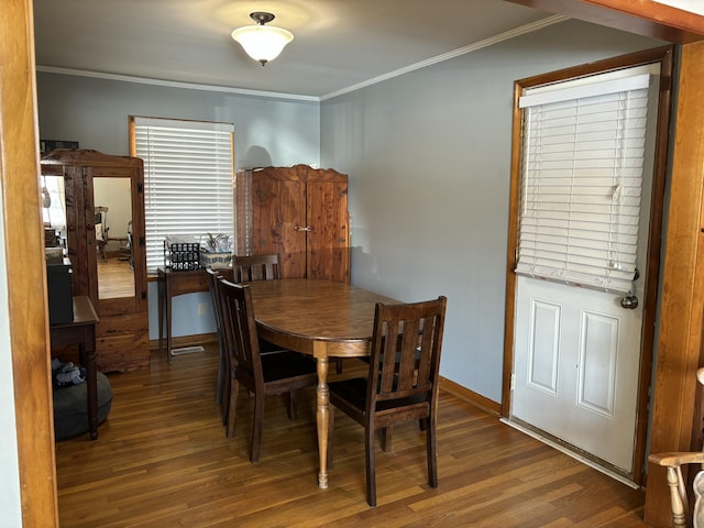 dining space featuring dark wood-style floors, ornamental molding, and baseboards