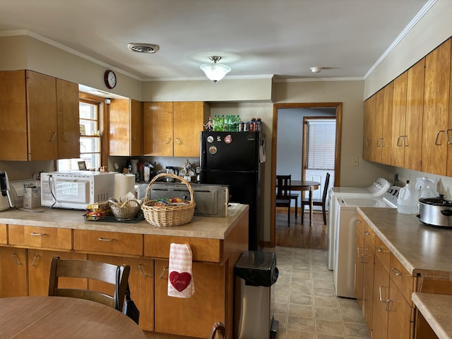 kitchen featuring light countertops, washing machine and dryer, freestanding refrigerator, and brown cabinets