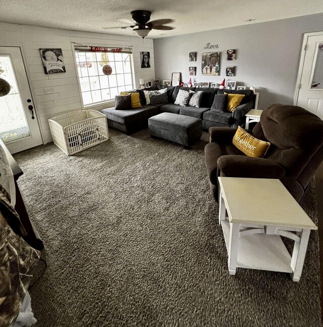 living room with carpet floors, ceiling fan, and a textured ceiling