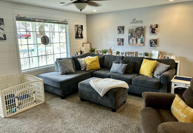 living area featuring wooden walls, ceiling fan, and a textured ceiling