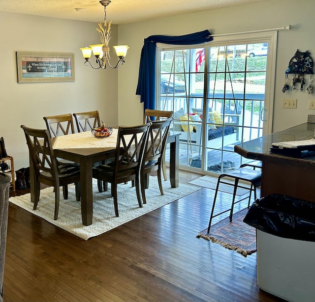 dining area with dark wood-style floors, a textured ceiling, and a notable chandelier