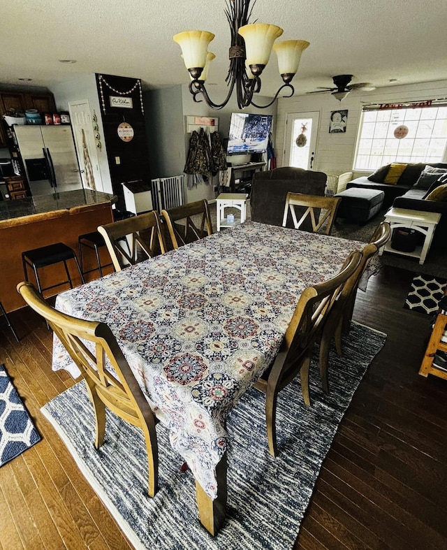 dining space featuring dark wood finished floors, a textured ceiling, and ceiling fan with notable chandelier