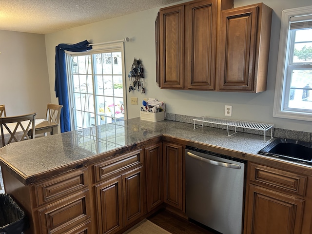 kitchen featuring tile countertops, a sink, a peninsula, and dishwasher