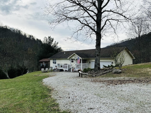 ranch-style house featuring gravel driveway and a front lawn