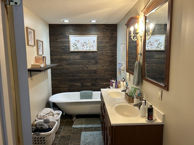 bathroom featuring wooden walls, a freestanding bath, a textured ceiling, and a sink