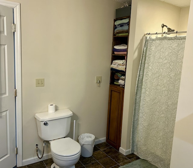 bathroom featuring curtained shower, toilet, and baseboards