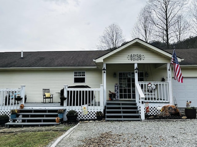 view of front of property with a garage, covered porch, and roof with shingles