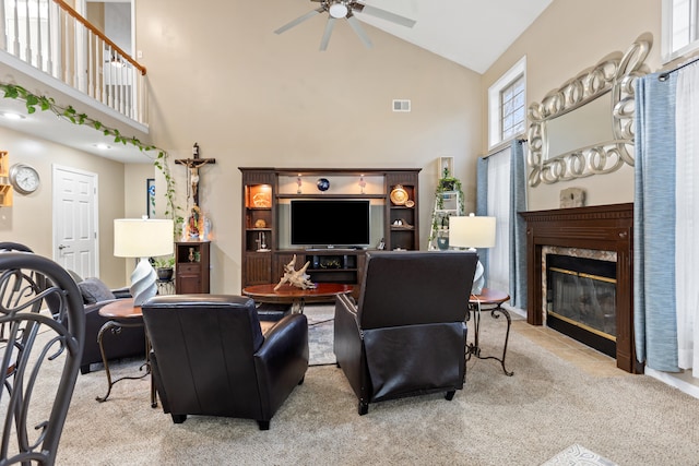 living room featuring light colored carpet, a high end fireplace, visible vents, and ceiling fan