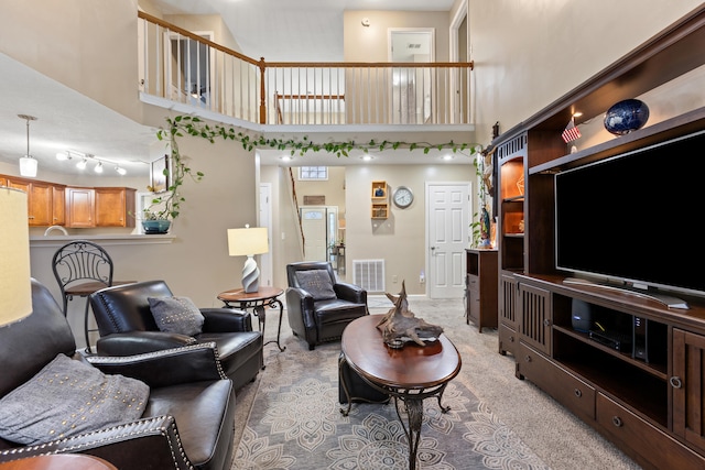 living area with baseboards, visible vents, light carpet, and a high ceiling