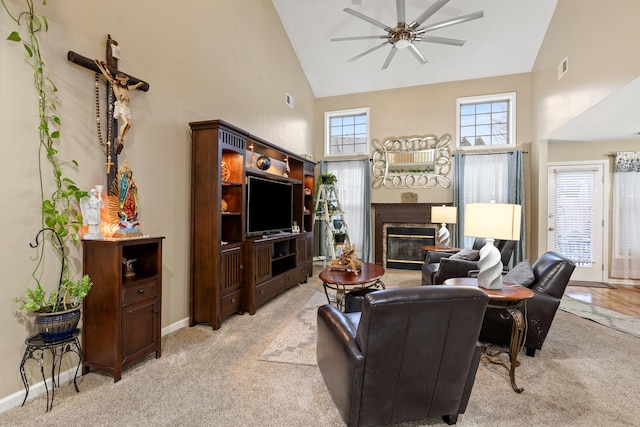 living area with light carpet, high vaulted ceiling, a ceiling fan, and a glass covered fireplace