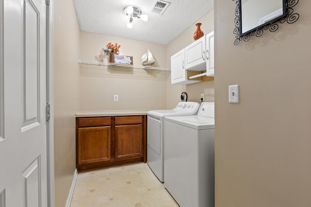 clothes washing area with cabinet space, visible vents, separate washer and dryer, and a textured ceiling