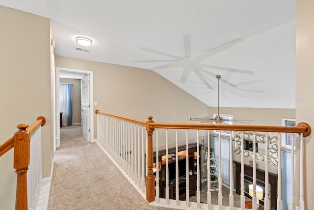 corridor with an upstairs landing, baseboards, vaulted ceiling, and light colored carpet