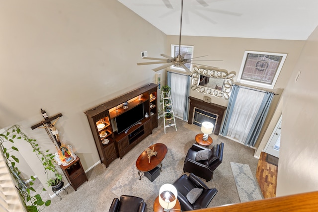 living area featuring baseboards, a ceiling fan, a glass covered fireplace, vaulted ceiling, and carpet floors