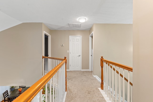 corridor with baseboards, light carpet, visible vents, and an upstairs landing