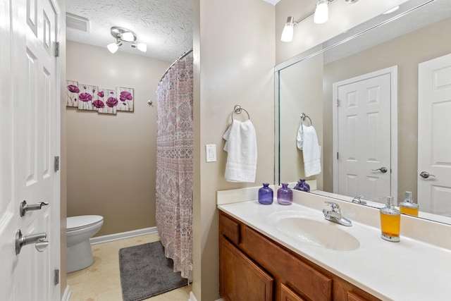 bathroom featuring a textured ceiling, toilet, visible vents, vanity, and baseboards