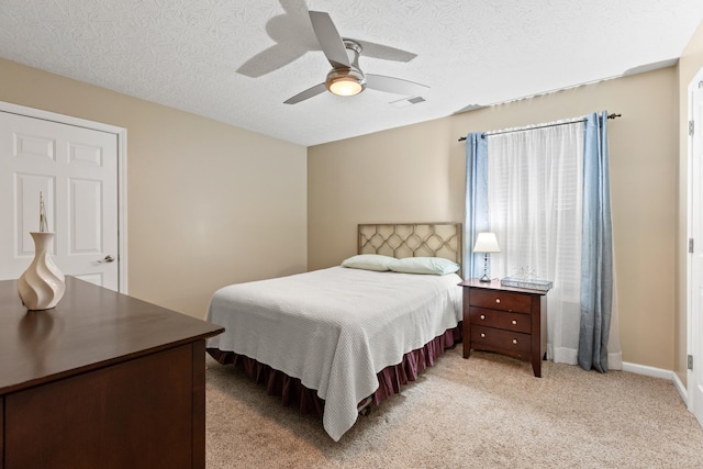 bedroom with light carpet, baseboards, visible vents, ceiling fan, and a textured ceiling