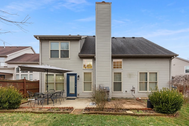 rear view of property with a shingled roof, a chimney, a patio area, and fence