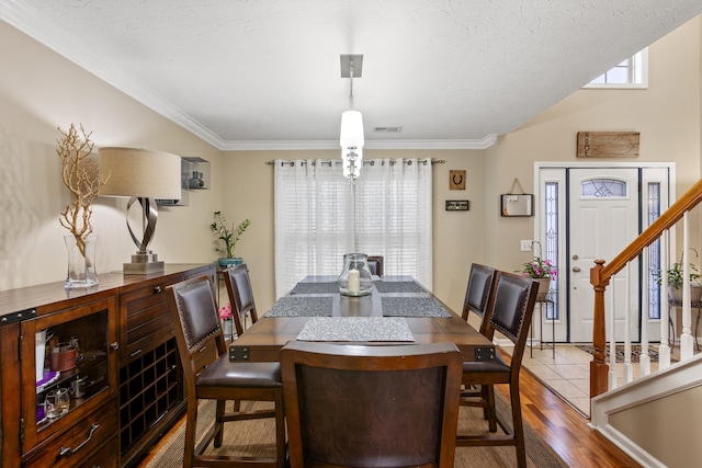 dining space with stairs, ornamental molding, a textured ceiling, and wood finished floors