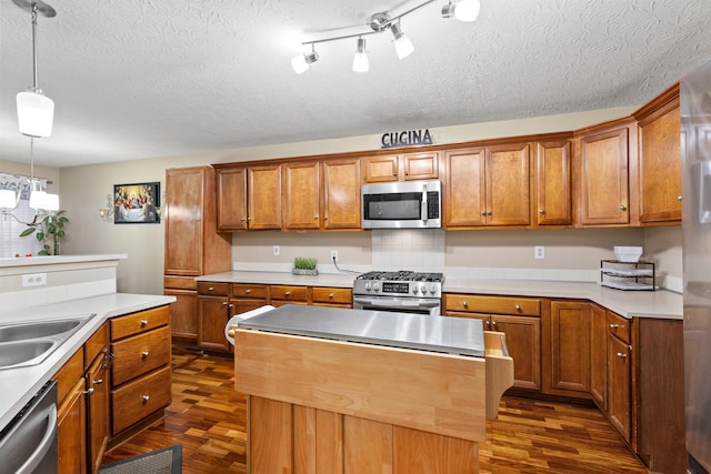 kitchen featuring stainless steel appliances, a center island, hanging light fixtures, light countertops, and brown cabinets