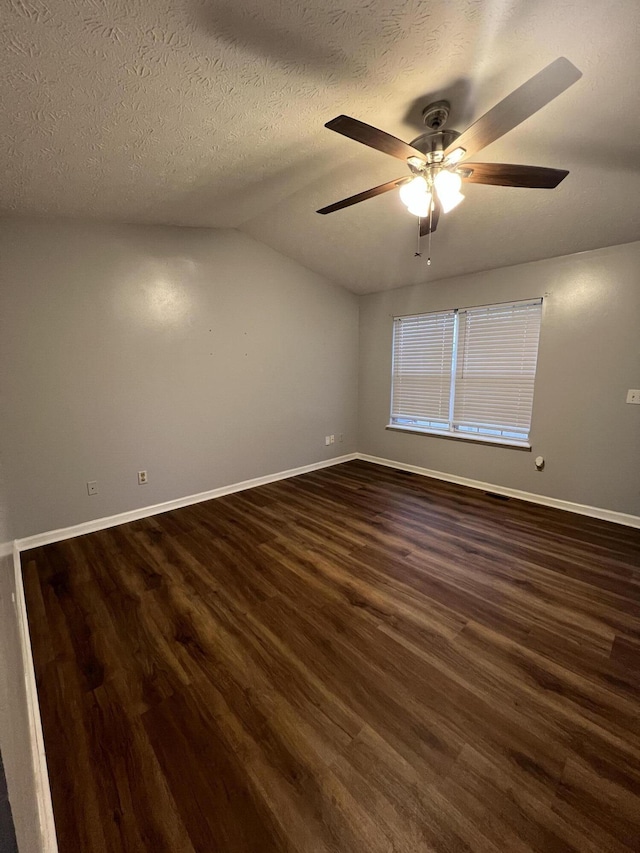 spare room with lofted ceiling, dark wood-type flooring, ceiling fan, a textured ceiling, and baseboards