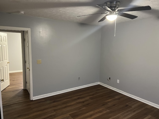 spare room with dark wood finished floors, a textured ceiling, and baseboards