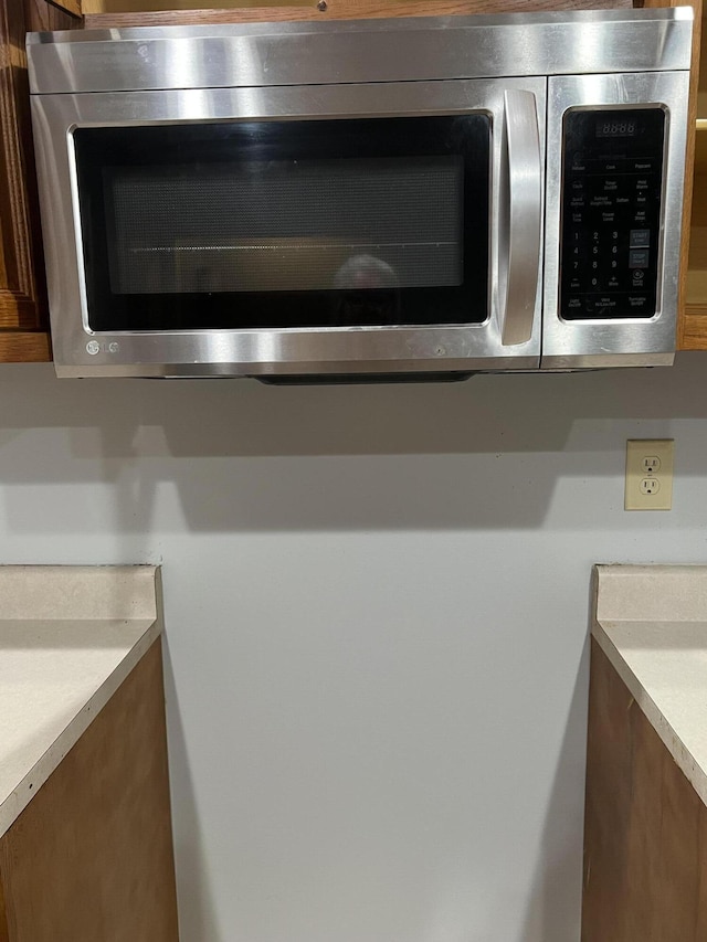 room details featuring brown cabinetry, light countertops, and stainless steel microwave