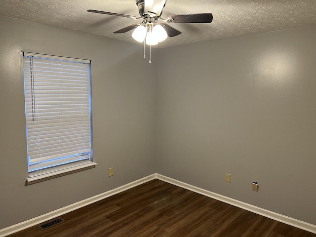 spare room with dark wood-style floors, baseboards, visible vents, and a textured ceiling