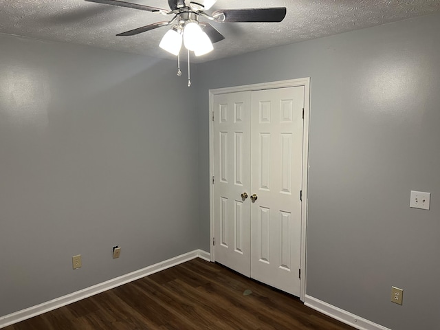 unfurnished bedroom featuring baseboards, a ceiling fan, dark wood-style floors, a textured ceiling, and a closet