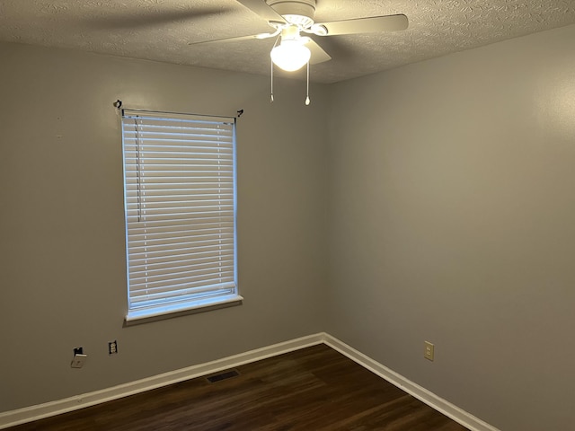 unfurnished room with ceiling fan, a textured ceiling, dark wood-style flooring, visible vents, and baseboards