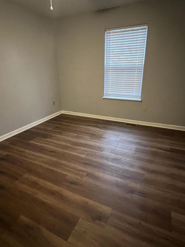 empty room featuring baseboards and dark wood-type flooring