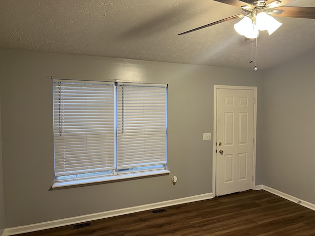 empty room featuring baseboards, visible vents, a ceiling fan, dark wood-style flooring, and a textured ceiling