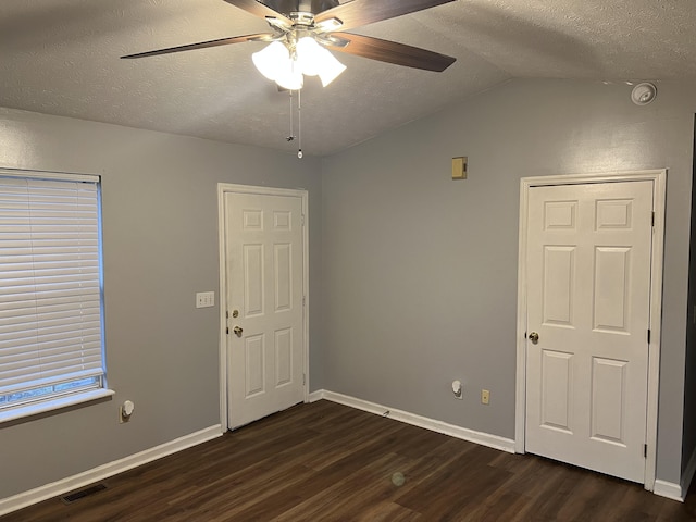 spare room with a textured ceiling, ceiling fan, dark wood-type flooring, visible vents, and baseboards