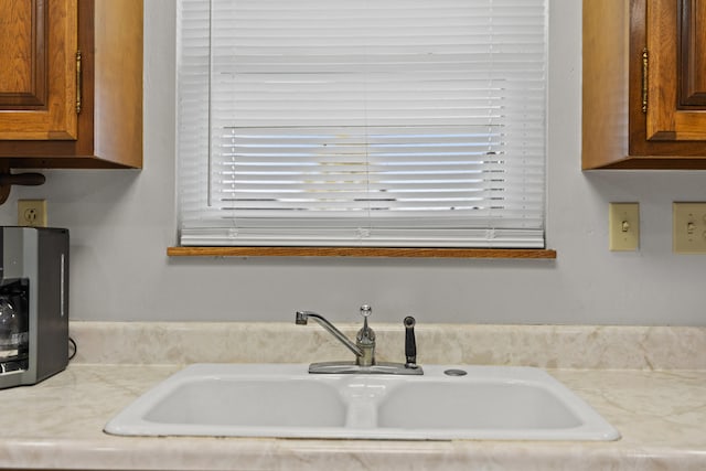 details with brown cabinetry, light countertops, and a sink