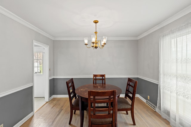 dining space with ornamental molding, light wood-type flooring, baseboards, and an inviting chandelier