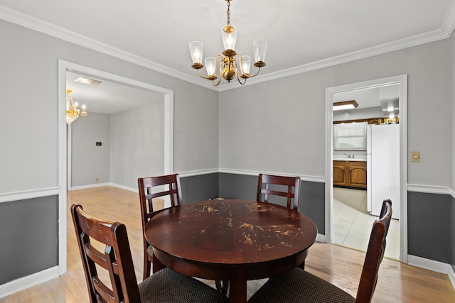 dining area with an inviting chandelier, baseboards, light wood finished floors, and crown molding