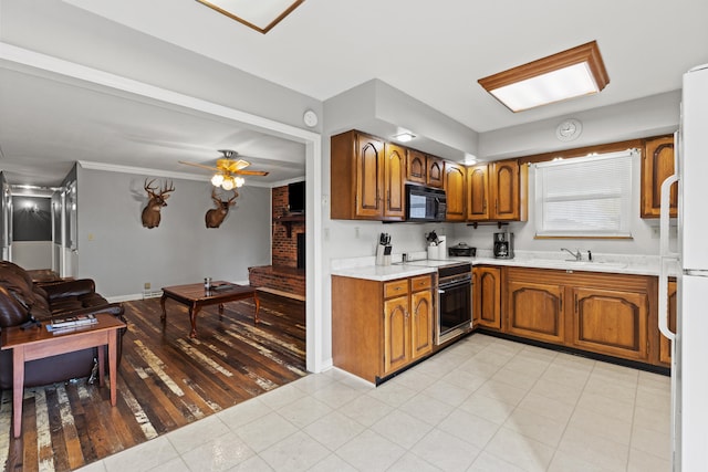 kitchen with brown cabinets, light countertops, black microwave, a sink, and range with electric stovetop