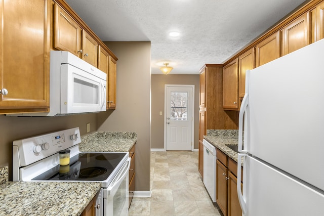 kitchen with white appliances, light stone counters, brown cabinets, and a textured ceiling