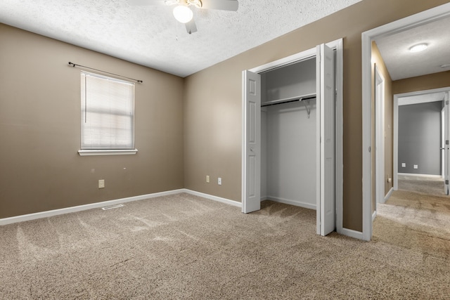 unfurnished bedroom with baseboards, ceiling fan, carpet, a textured ceiling, and a closet