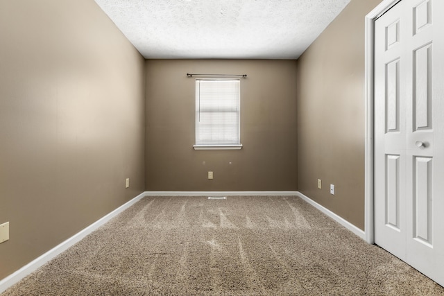 carpeted empty room with baseboards and a textured ceiling