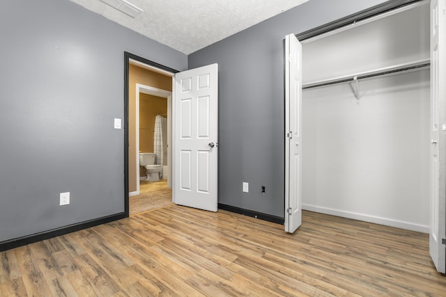 unfurnished bedroom with light wood-style flooring, a closet, baseboards, and a textured ceiling