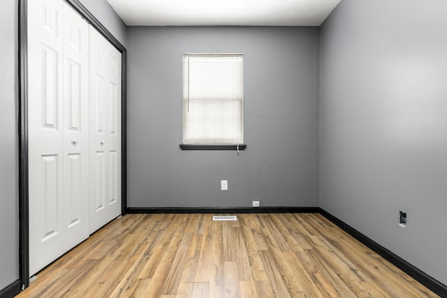 unfurnished bedroom featuring light wood finished floors, a closet, visible vents, and baseboards