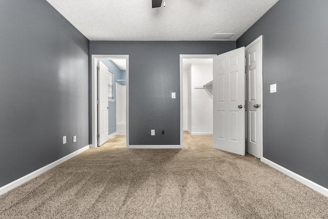 unfurnished bedroom featuring a spacious closet, baseboards, and carpet flooring