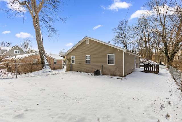 snow covered back of property featuring central AC and fence