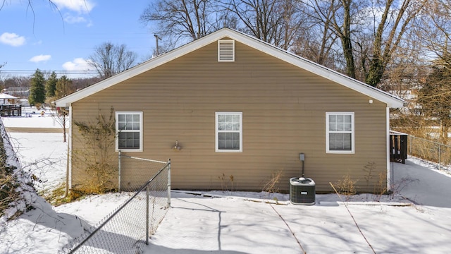 snow covered back of property with central AC and fence