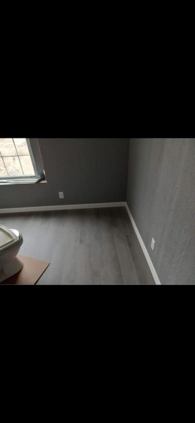 unfurnished room with baseboards and wood finished floors