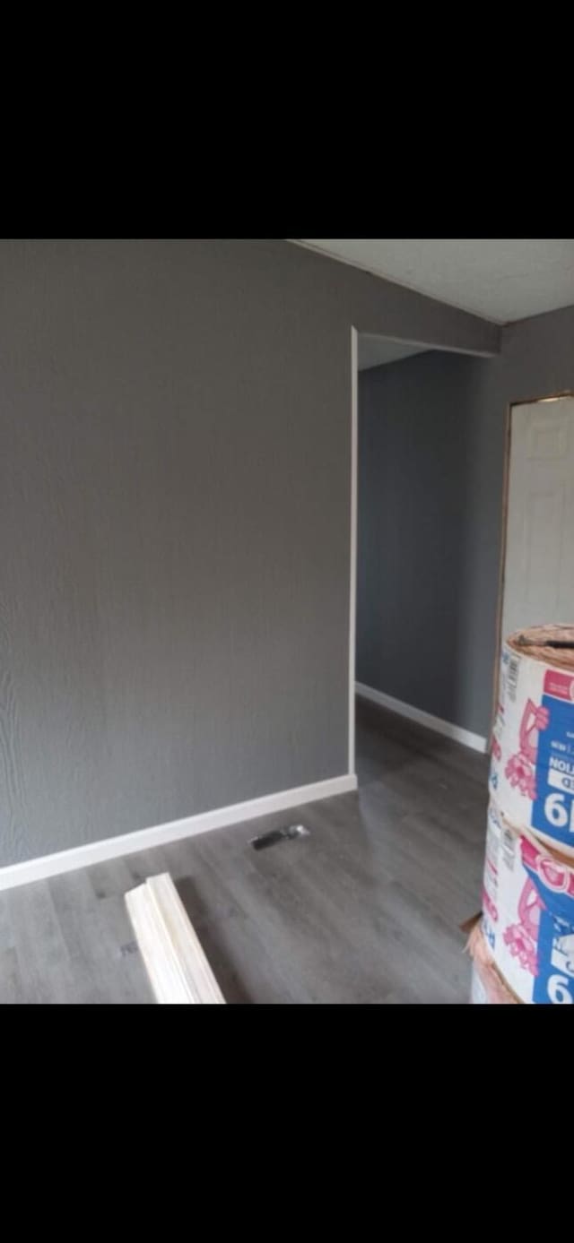 empty room featuring wood finished floors, visible vents, and baseboards