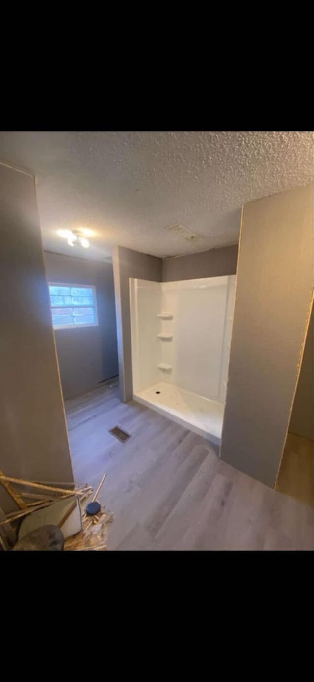 hallway with a textured ceiling and light wood-type flooring