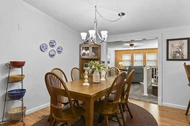 dining space featuring crown molding, a textured ceiling, baseboards, and wood finished floors